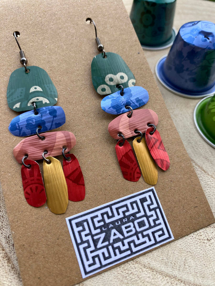 bright, colourful, green, blue, red, gold earrings made from recycled nespresso capsules on a wooden background and Laura Zabo logo and a few nespresso pods