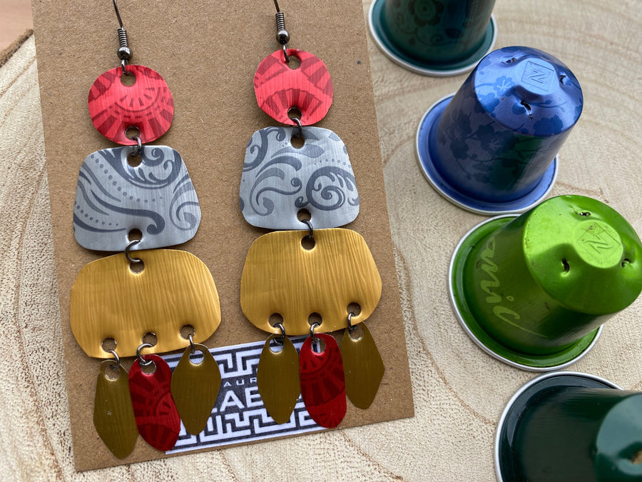 large, long, red, silver, golden earrings made from upcycled nespresso capsules on a wooden background decorated with few nespresso pods