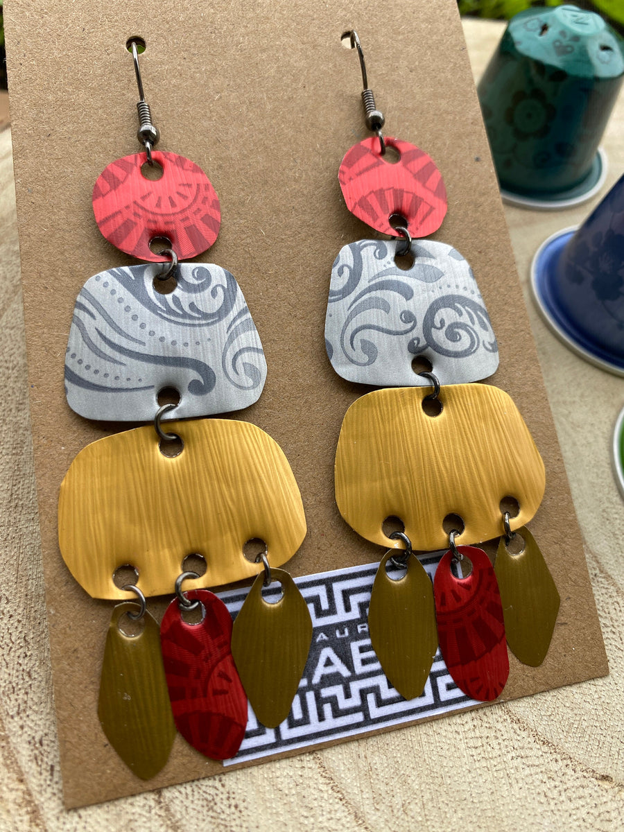 large, long, red, silver, golden earrings made from upcycled nespresso capsules on a wooden background decorated with few nespresso pods