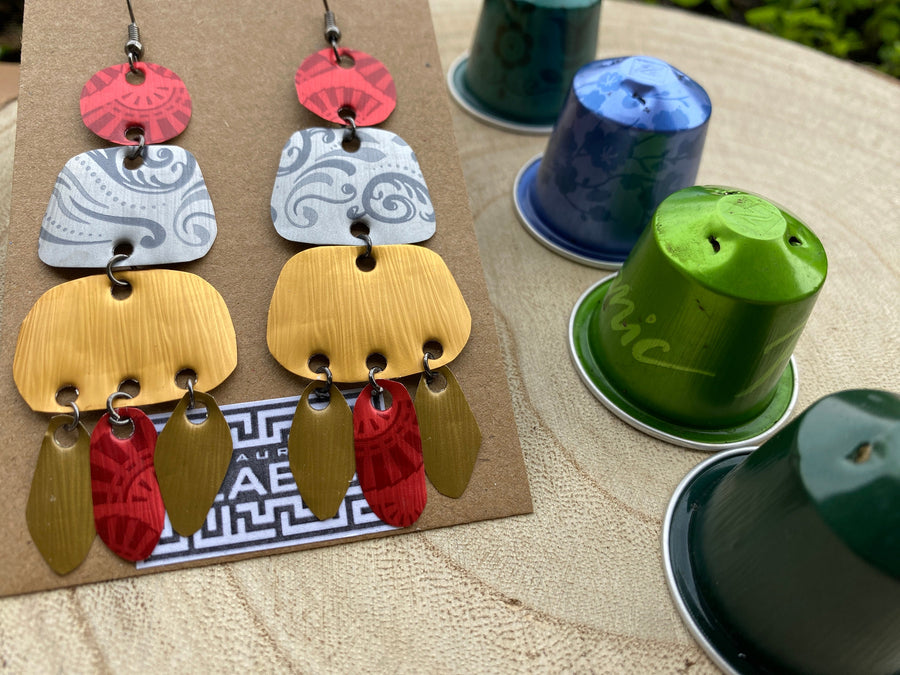 large, long, red, silver, golden earrings made from upcycled nespresso capsules on a wooden background decorated with few nespresso pods