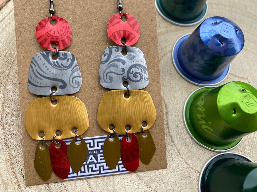 large, long, red, silver, golden earrings made from upcycled nespresso capsules on a wooden background decorated with few nespresso pods