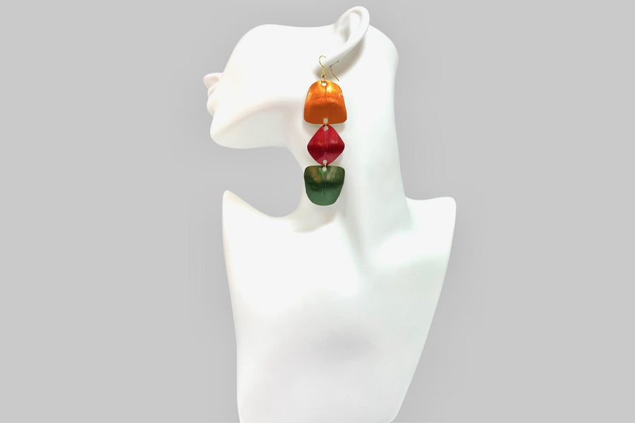 orange, red, green geometric earrings made from upcycled nespresso pods, on a white mannequin and grey background