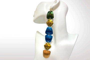 extra long, colourful, green, gold, blue statement earrings made from upcycled nespresso capsules on a white mannequin and background