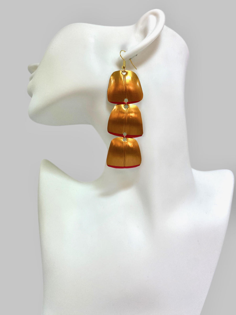 Gold red geometric and asymmetric earring made from upcycled upcycled nespresso capsules on a mannequin and grey background