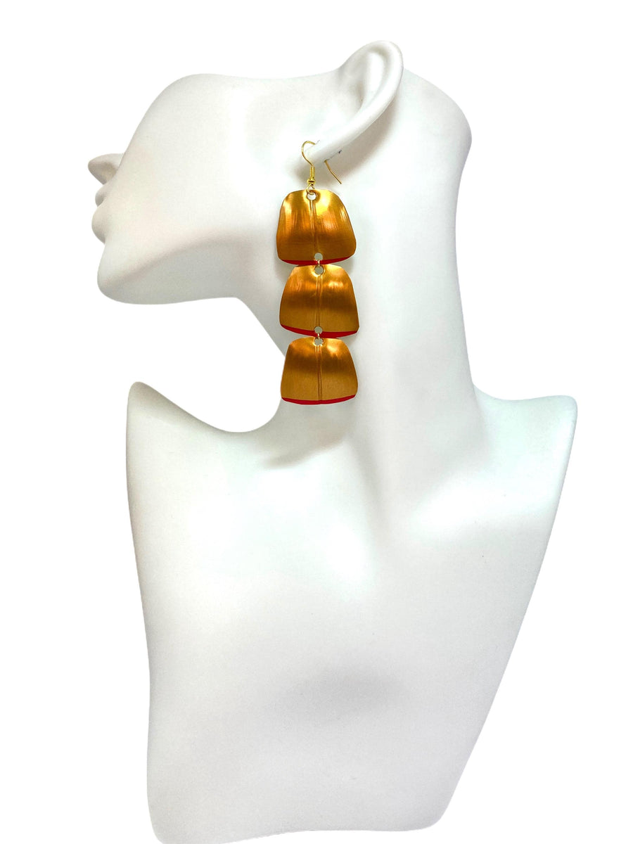 Gold red geometric and asymmetric earring made from upcycled upcycled nespresso capsules on a mannequin and white background