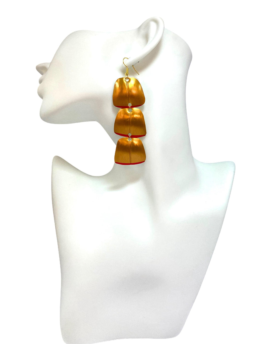 Gold red geometric and asymmetric earring made from upcycled upcycled nespresso capsules on a mannequin and white background