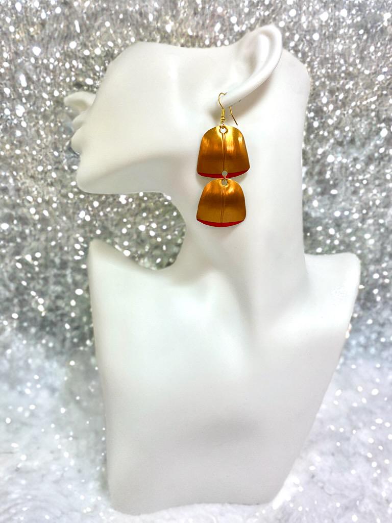 Gold red geometric and asymmetric earring made from upcycled upcycled nespresso capsules on a mannequin and glitter background