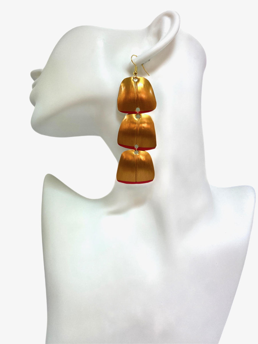 Gold red geometric and asymmetric earring made from upcycled upcycled nespresso capsules on a mannequin and white background