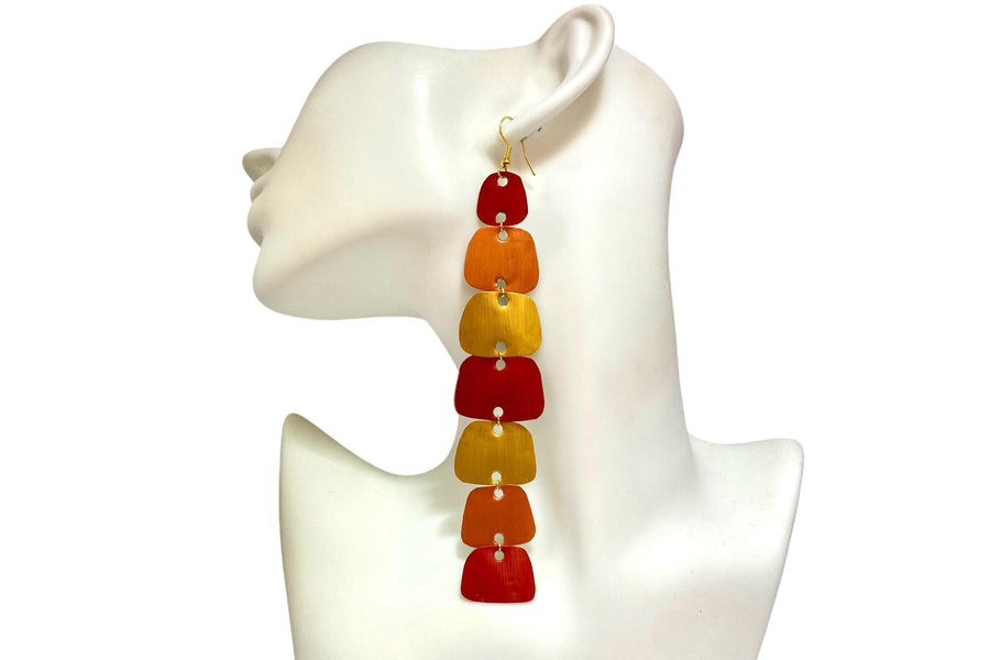 long, red, peach, gold earrings made from nespresso capsules on a white mannequin