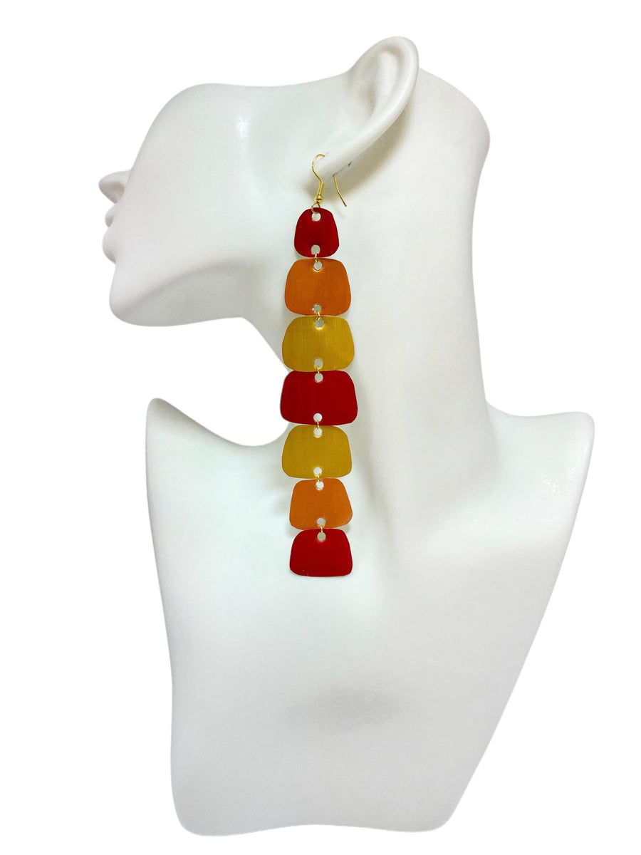 long, red, peach, gold earrings made from nespresso capsules on a white mannequin