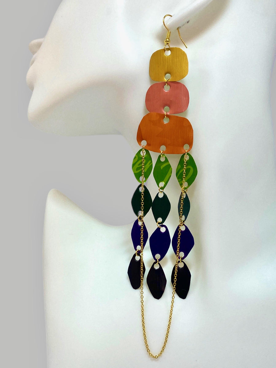 large, rainbow coloured chandelier earrings made from colourful Nespresso pods with a golden chain, on a white mannequin and grey background