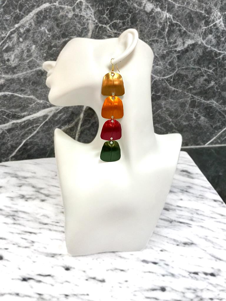 gold orange red green statement earrings made from Upcycled nespresso capsules on a white mannequin and marble background