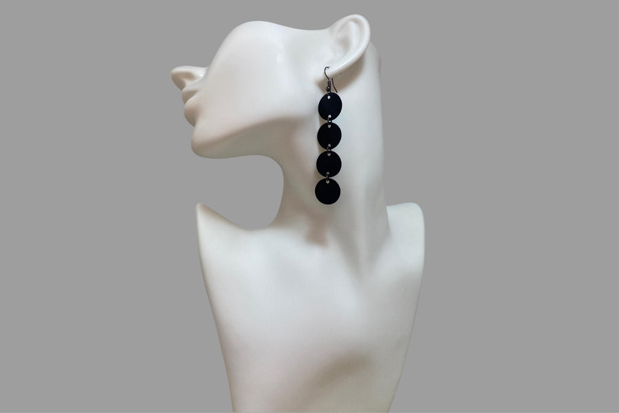 black circle design earrings made from upcycled bicycle inner tube on a white mannequin and grey background