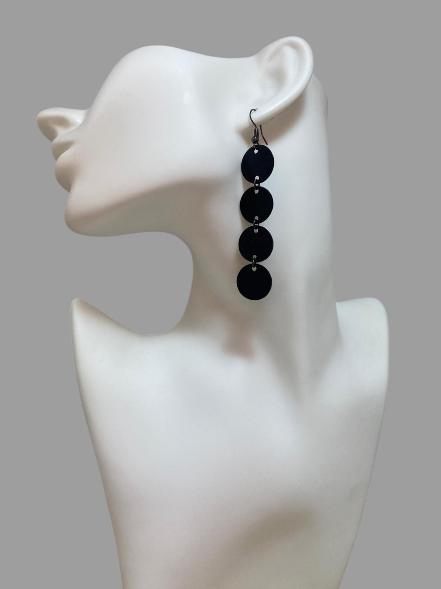 black circle design earrings made from upcycled bicycle inner tube on a white mannequin and grey background