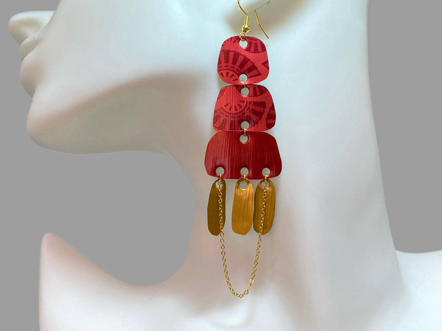 Golden red large earrings made from upcycled nespresso capsules on a white earrings display and grey background