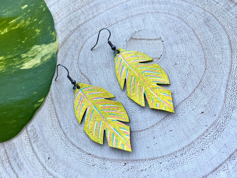 yellow coloured upcycled bicycle inner tube, tyre rubber earrings on a wooden background and a green  leaf