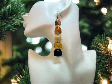 earthy coloured, brown black gold long earrings made from upcycled nespresso capsules on white mannequin and xmas tree background