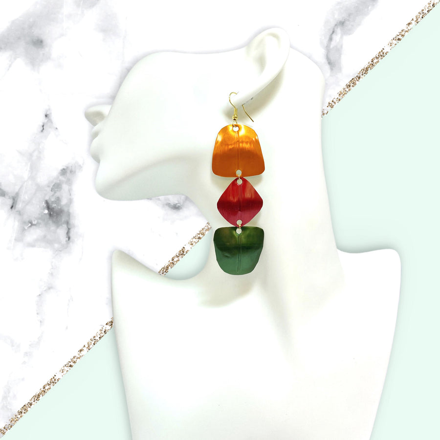 orange, red, green geometric earrings made from upcycled nespresso pods, on a white mannequin and marble background