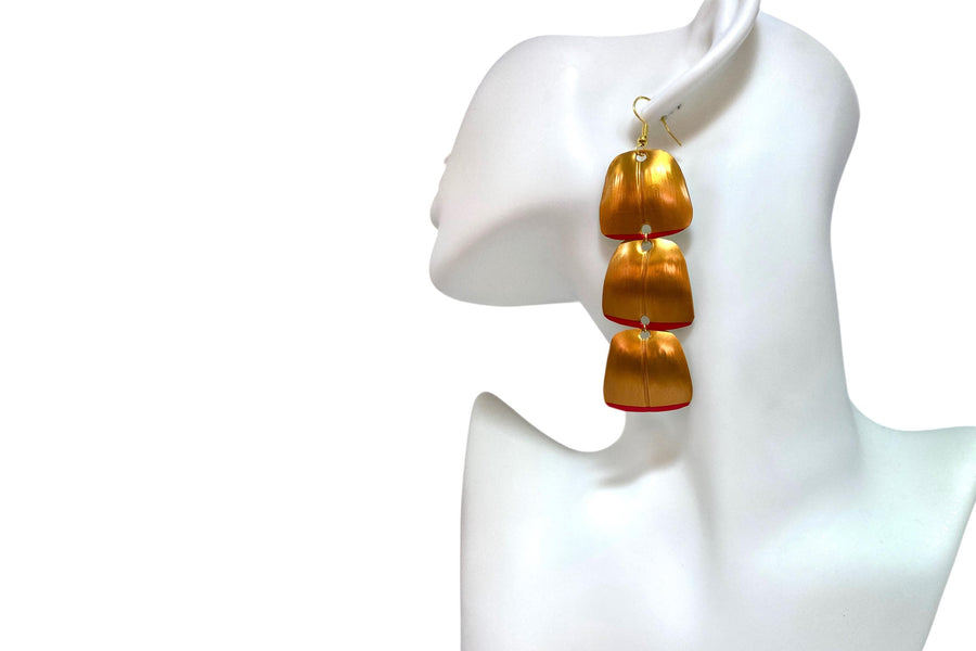 Gold red geometric and asymmetric earring made from upcycled upcycled nespresso capsules on a mannequin and white background