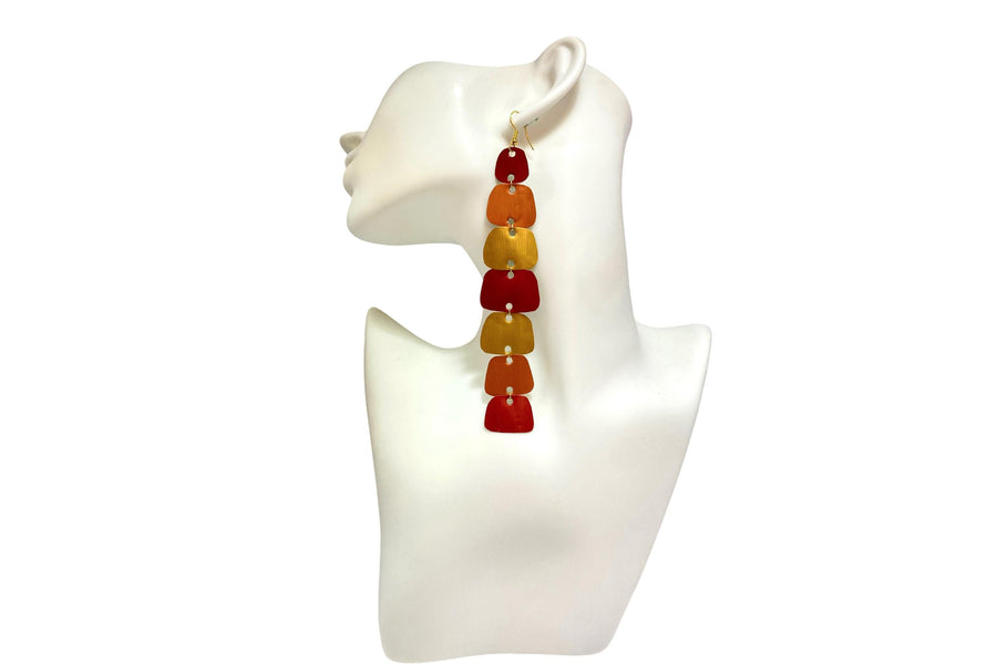 long, red, peach, gold earrings made from nespresso capsules on a white mannequin