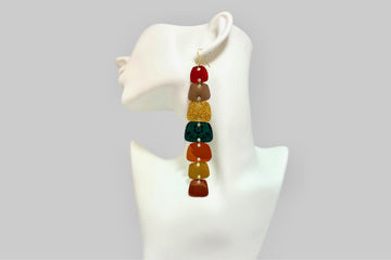 long, multicoloured earrings, each shape is cut from upcycled nespresso pods, on a white mannequin and grey background