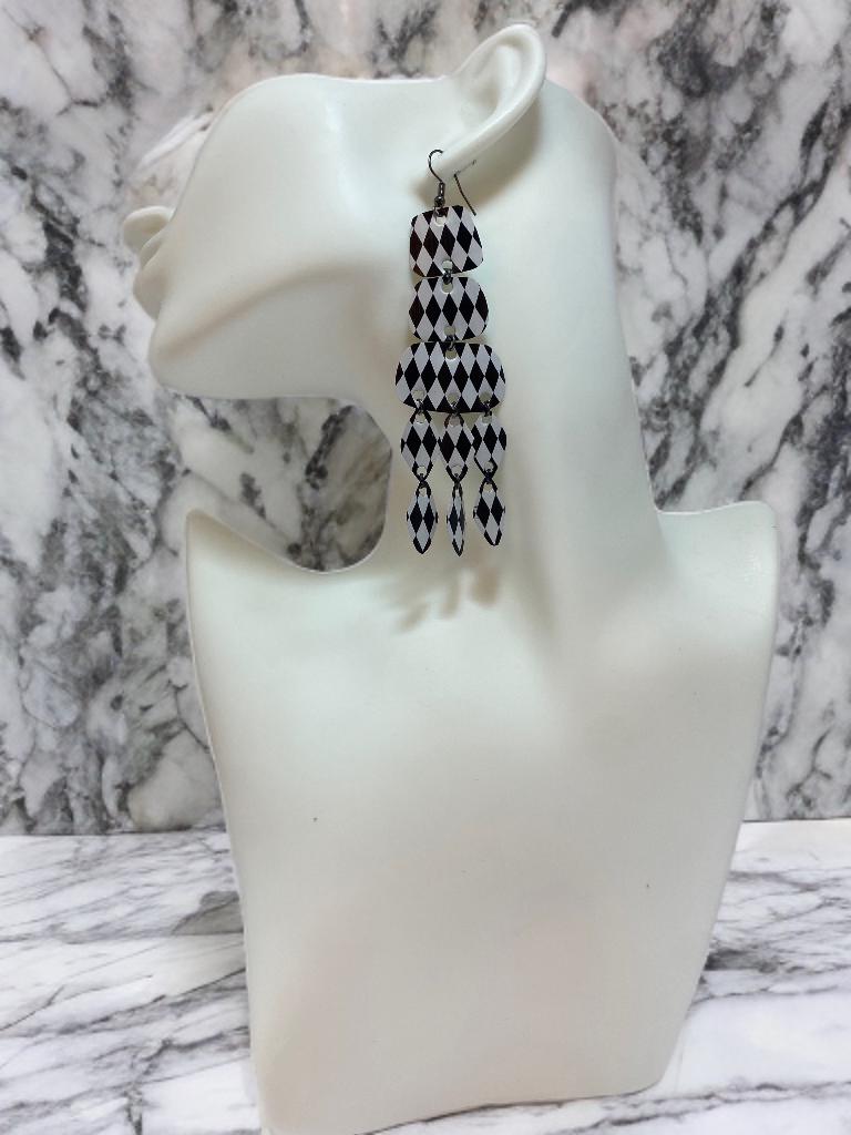 black and white upcycled chandelier earrings made from nespresso capsules on a white mannequin and marble  background