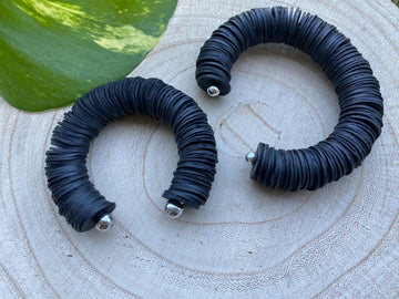 2 pieces of black, upcycled bicycle inner tube cuff bracelets on a wooden background