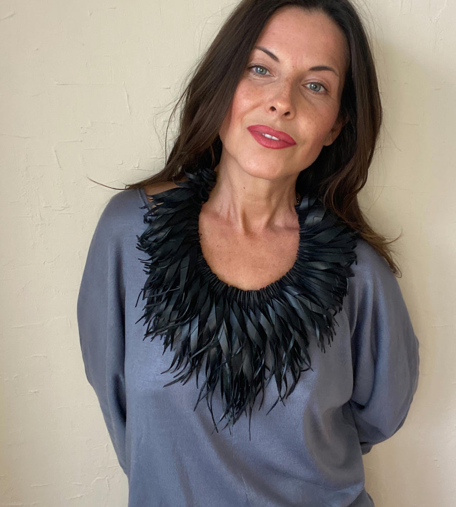 model wears large, quirky black, curly tassel necklace made from upcycled bicycle inner tube