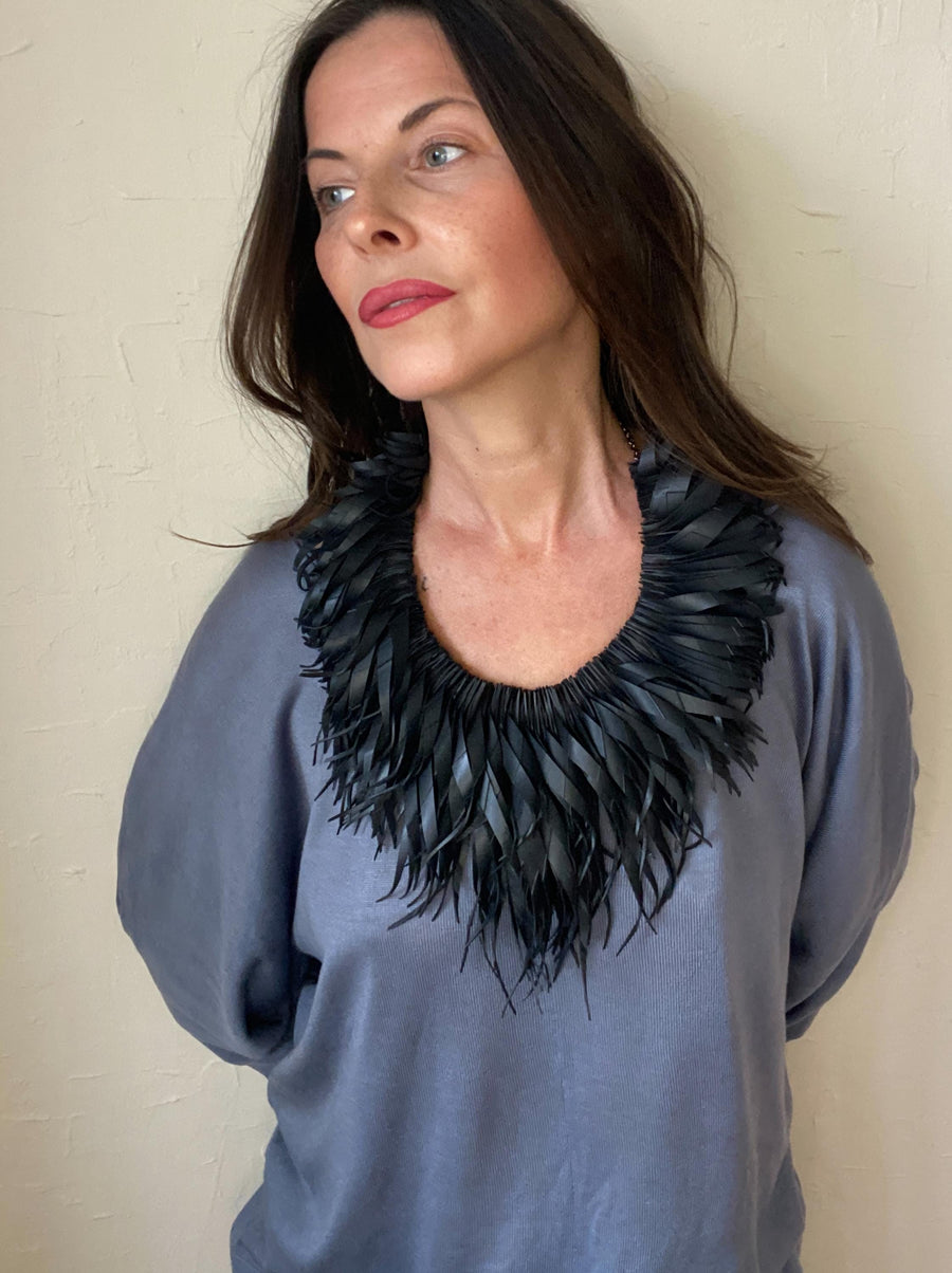 model wears large, quirky black, curly tassel necklace made from upcycled bicycle inner tube