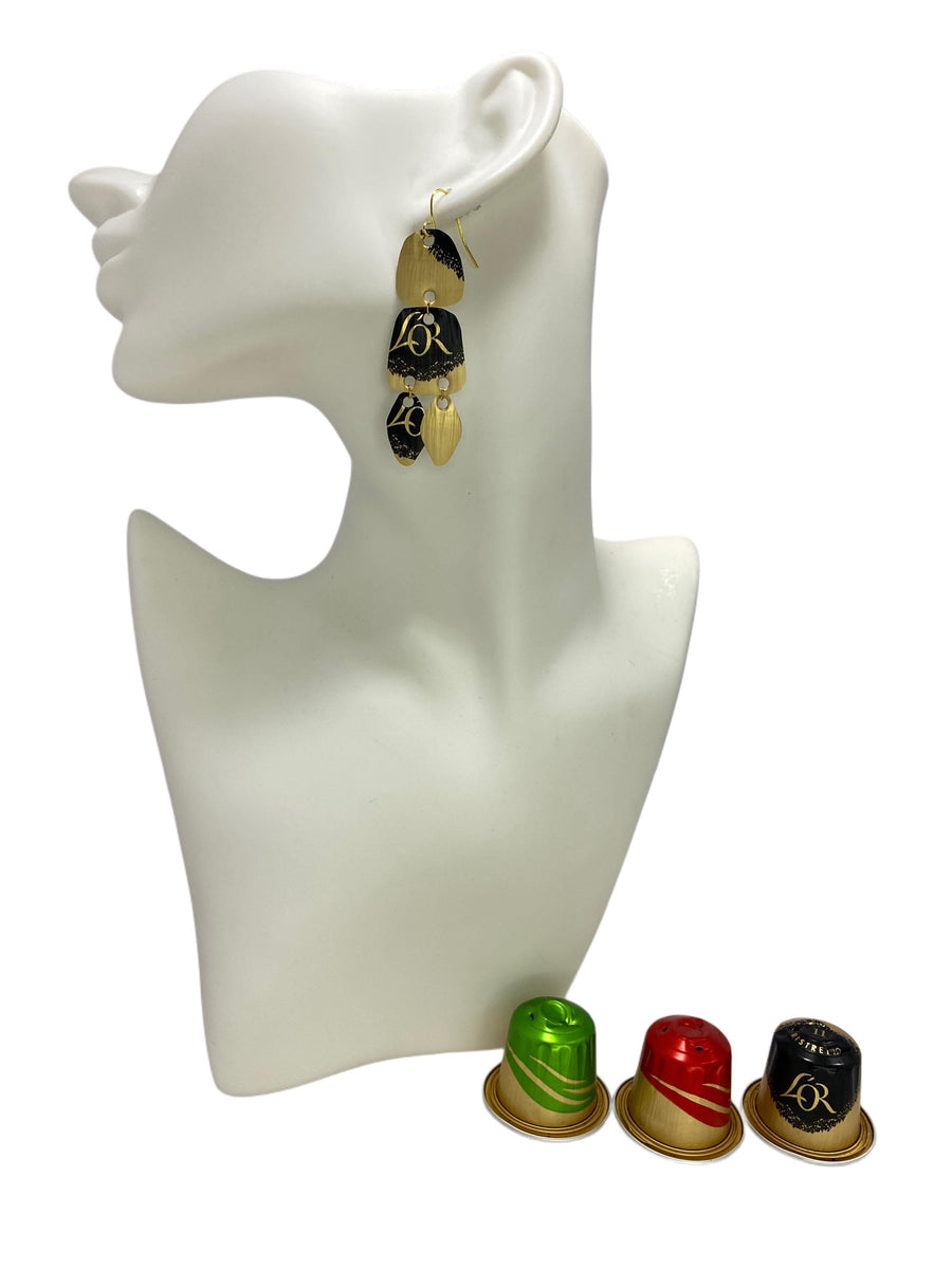 Upcycled, black-golden  Nespresso capsules earrings on a white mannequin display and 3 nespresso pods