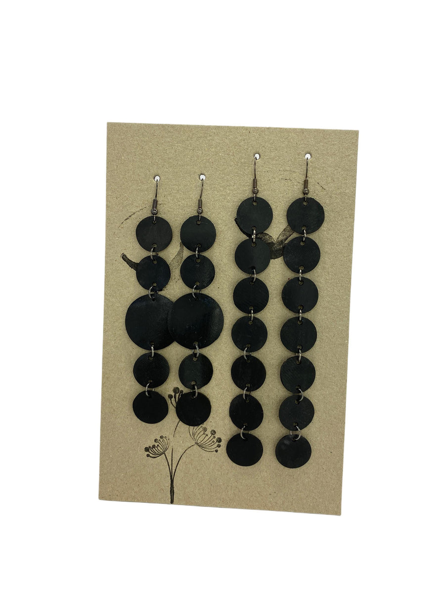 set of 2 earrings, black discs connected with jumprings made from upcycled bicycle inner tubes, on a carton paper background