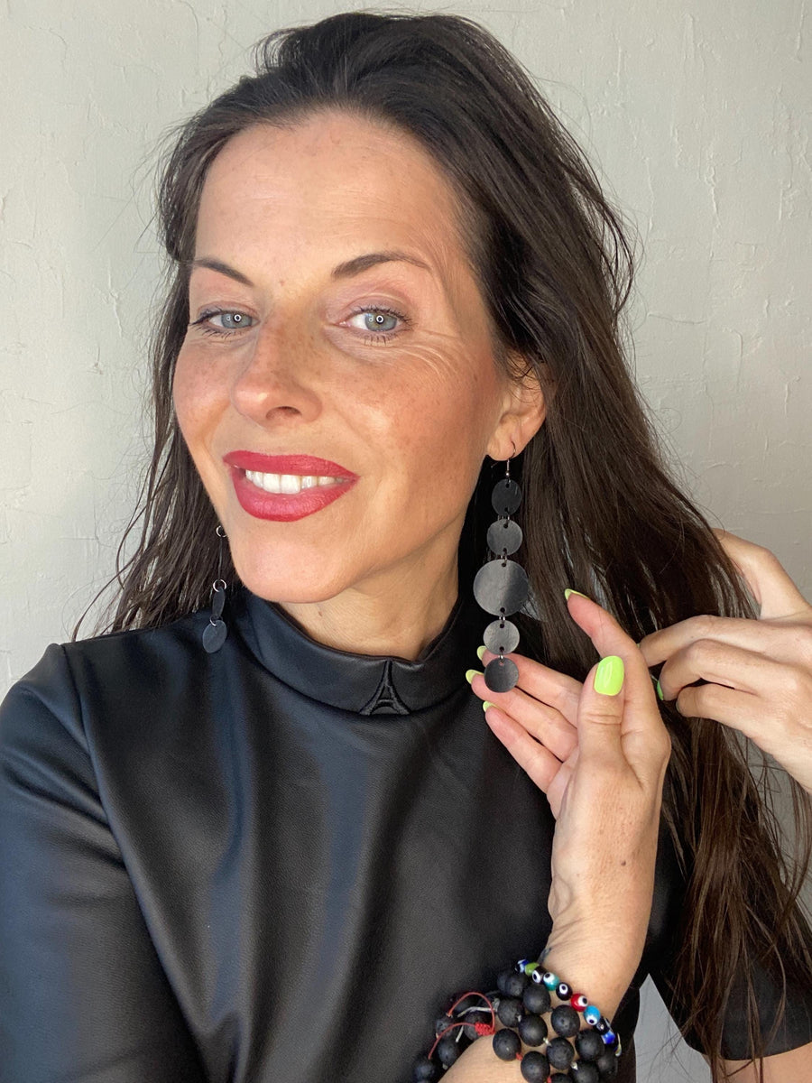 model wears black dress and upcycled bicycle inner tube disc earrings