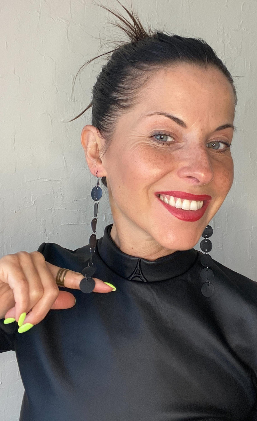 model wears black dress and upcycled bicycle inner tube disc earrings