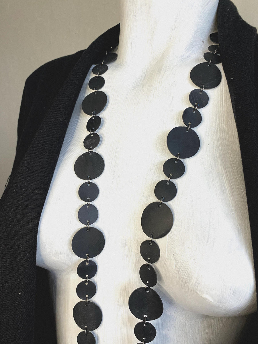 upcycled bicycle inner tube, disc shaped black  necklace displayed on a mannequin
