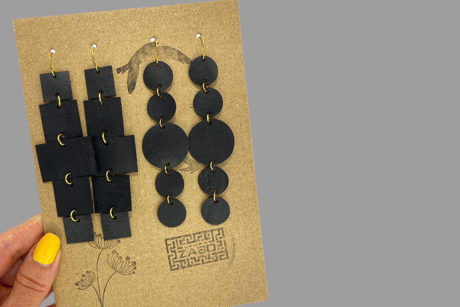 2 pairs of black golden upcycled bicycle inner tube, geometric earrings on a carton paper  display and grey background