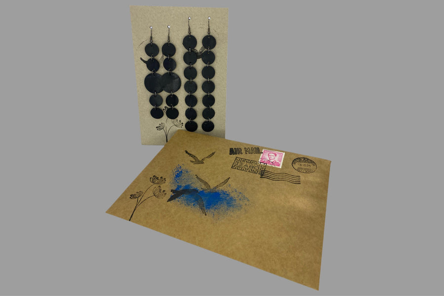 set of 2 earrings, black discs connected with jumprings made from upcycled bicycle inner tubes, on a carton paper background