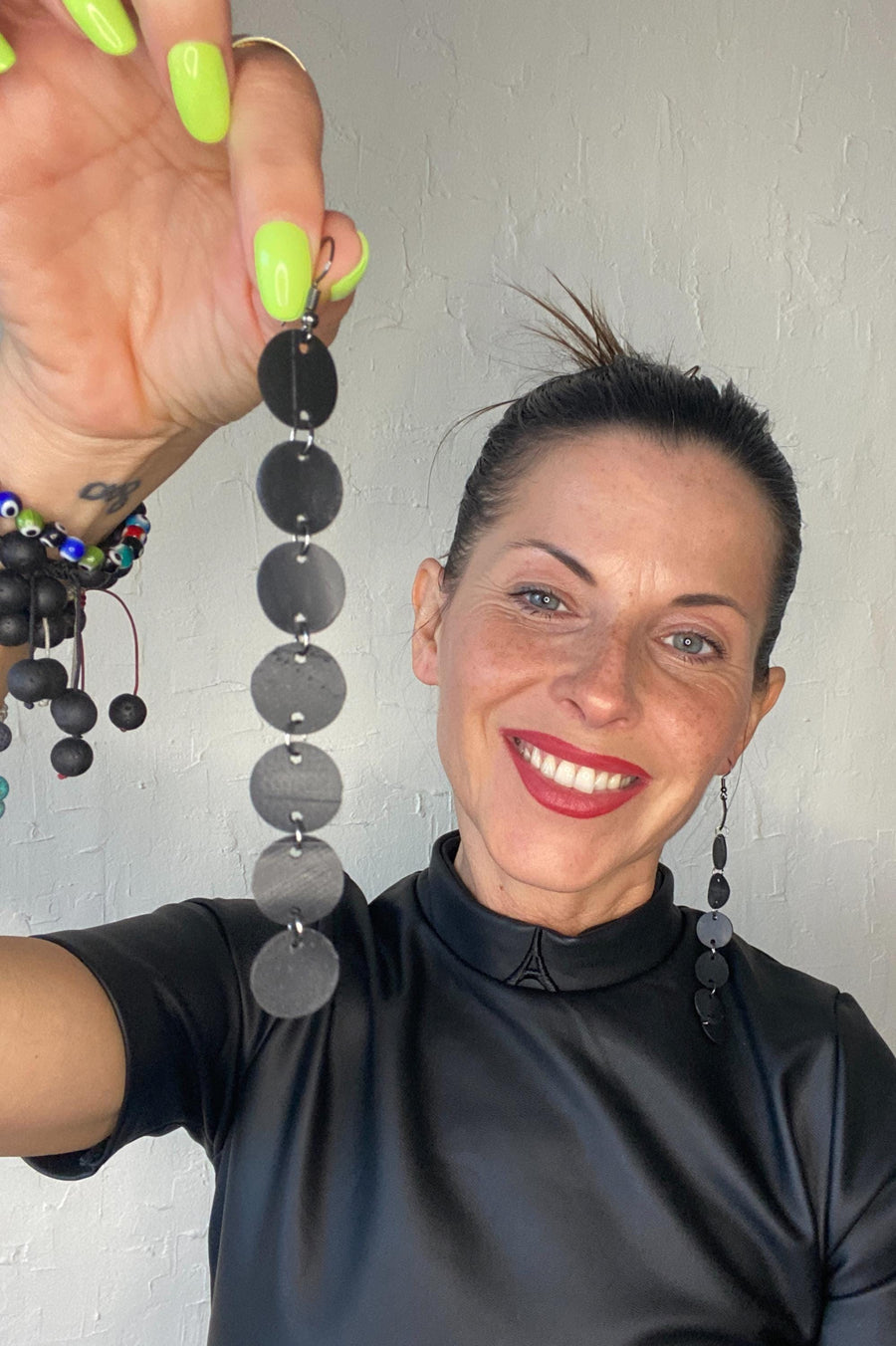 model wears black dress and upcycled bicycle inner tube disc earrings