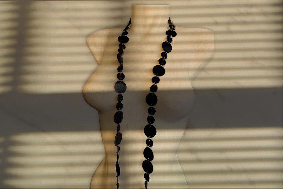 upcycled bicycle inner tube necklace, long, black wrap necklace on a white mannequin and darker background with shadows