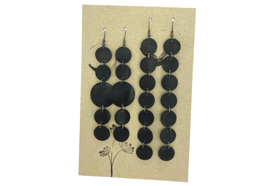 set of 2 earrings, black discs connected with jumprings made from upcycled bicycle inner tubes, on a carton paper background