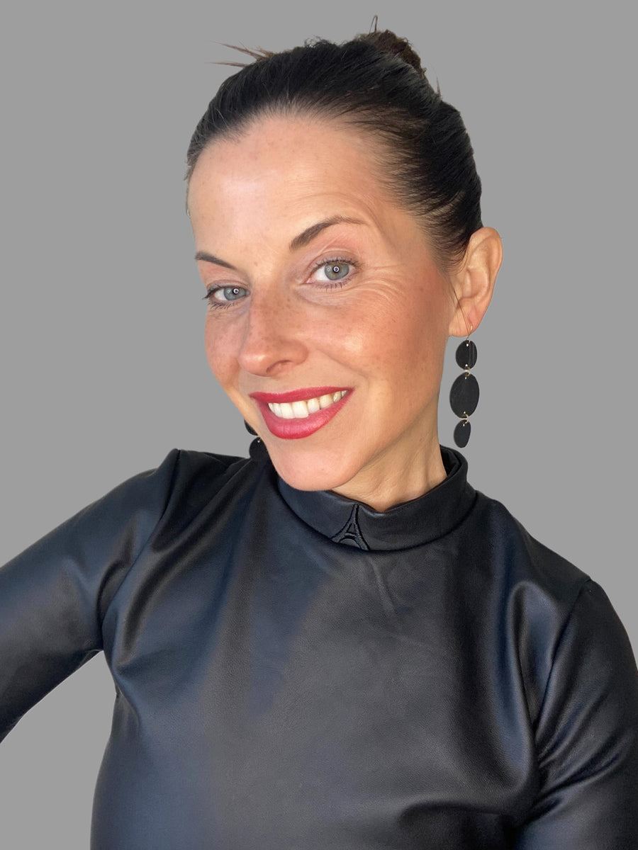 model wears black geometric, disc shaped earrings made from upcycled bicycle tyre rubber inner tube