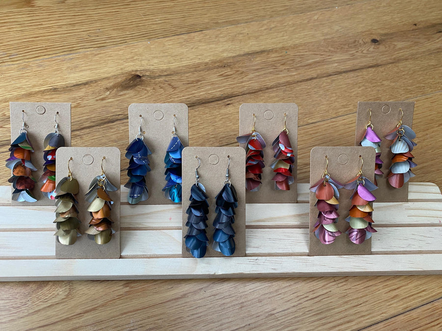 6 pairs of cascading earrings made from upcycled nespresso pods, capsules on a wooden display