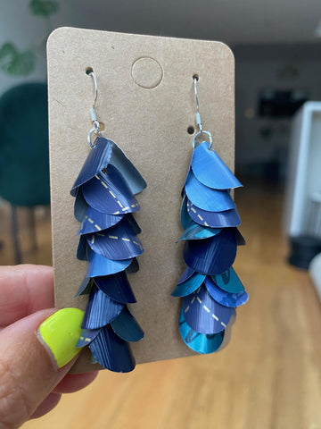 shades of blue, cascading earrings made from Nespresso capsules on a paper display