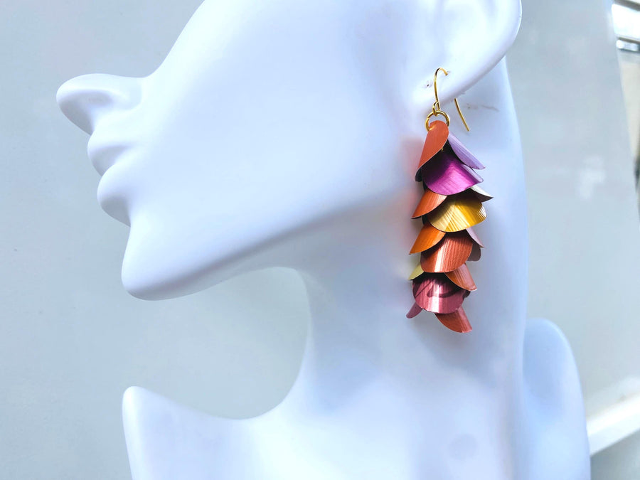 peach, orange, gold cascading earrings made from nespresso capsules on a white mannequin head
