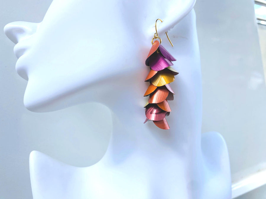 peach, orange, gold cascading earrings made from nespresso capsules on a white mannequin head