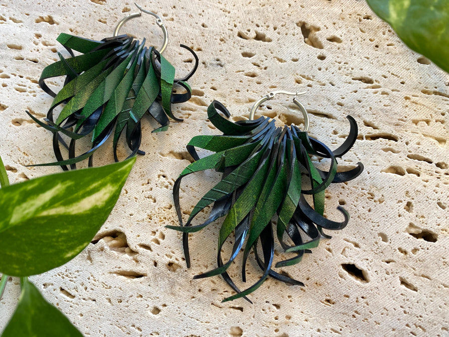 Pair of green, curly statement earrings made from upcycled bicycle inner tube rubber by laura zabo on a marble display