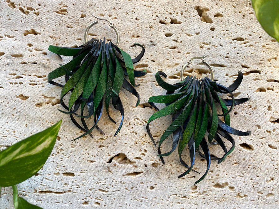Pair of green, curly statement earrings made from upcycled bicycle inner tube rubber by laura zabo on a marble display