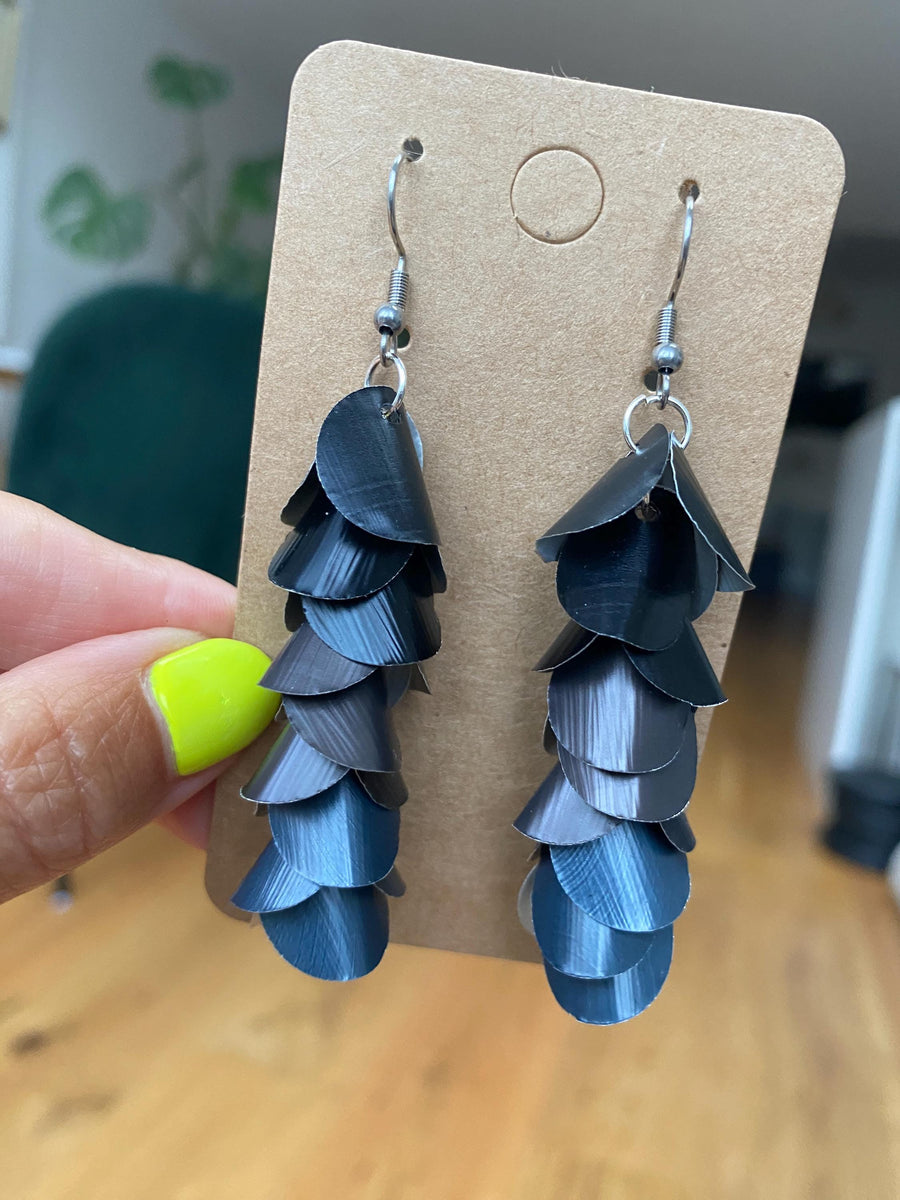 black grey cascading earrings made from upcycled nespresso pods on a paper display