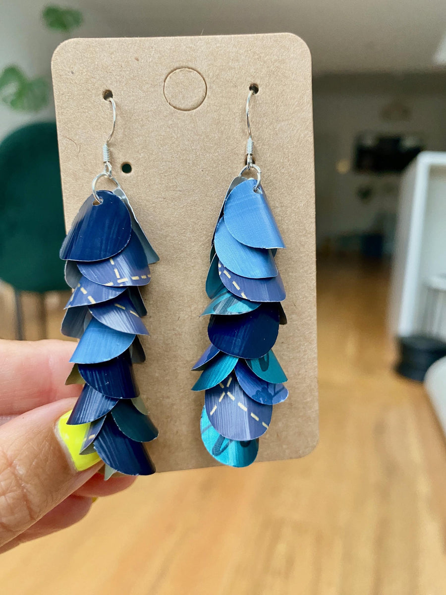 shades of blue, cascading earrings made from Nespresso capsules on a paper display