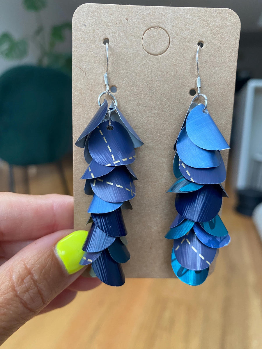 shades of blue, cascading earrings made from Nespresso capsules on a paper display
