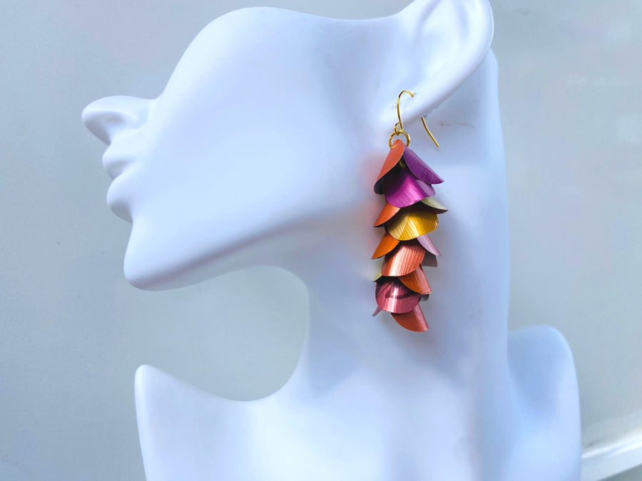 peach, orange, gold cascading earrings made from nespresso capsules on a white mannequin head
